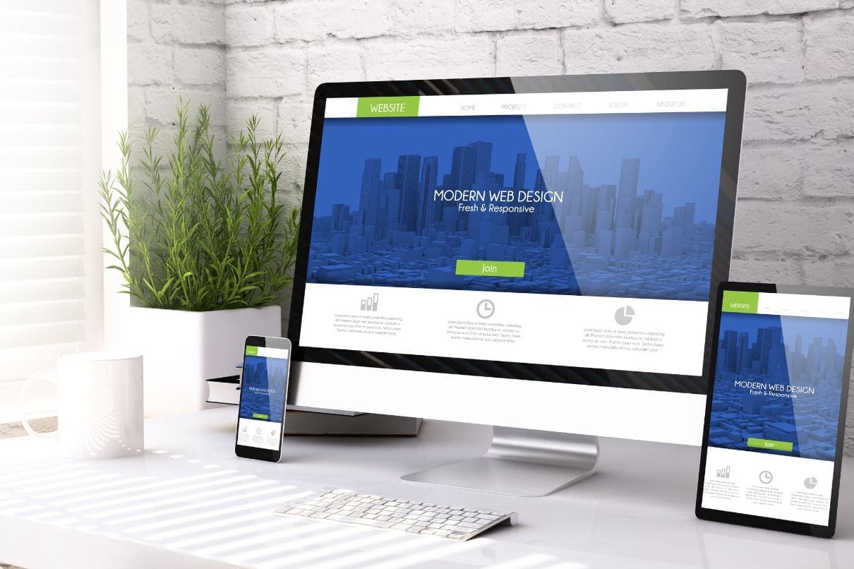 A desk with a desktop computer, laptop, and tablet.